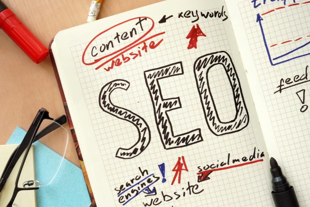 Notebook page with the word “SEO” written in large letters, surrounded by handwritten notes on content, keywords, search engines, social media, and website optimization.
