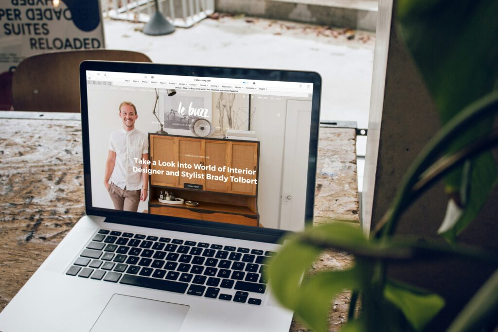 A laptop displaying a website about interior design on a rustic wooden table.